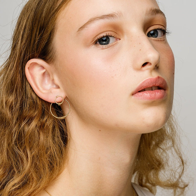 Boucles d'oreilles en vermeil Floreana portées par un modèle au cheveux bouclés