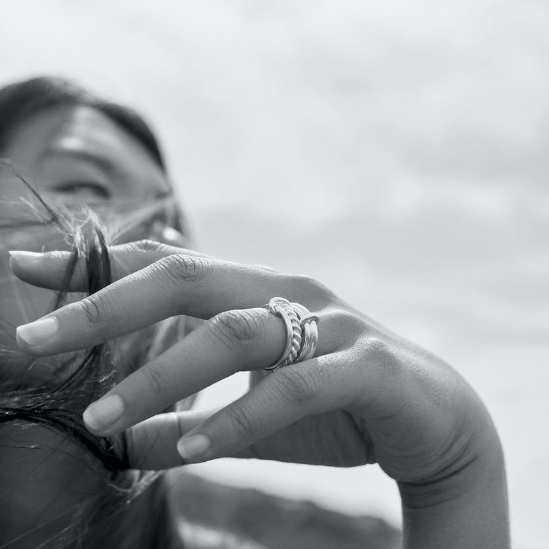 Black and white outdoor photo of a model wearing the silver Ellis ring and the silver Eden 3.2mm ring on her left hand.
