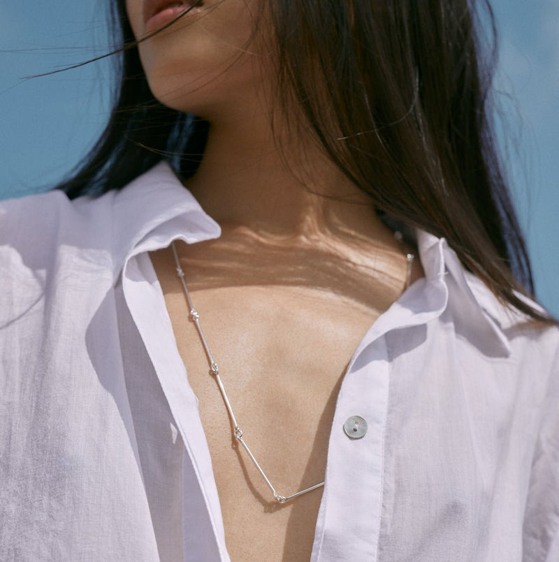Outdoor photo of a model wearing the Lou necklace in silver by Aurore Havenne, photographed by Alice Jacquemin
