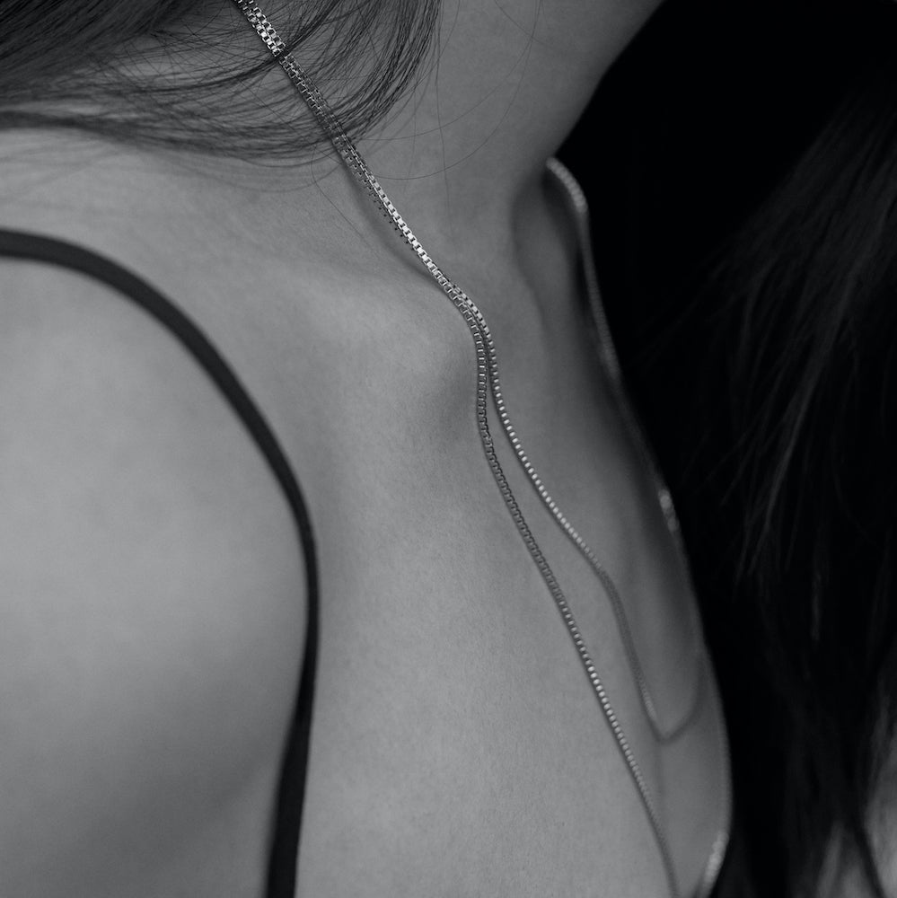 Black and white picture of a model wearing the Sacha necklace in silver. The Sacha necklace is in silver 925°°°.