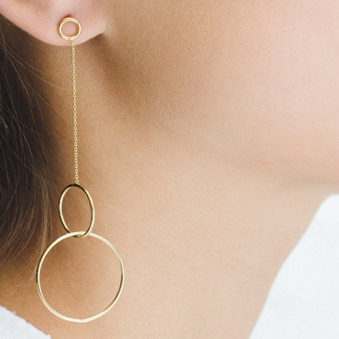 Photo of a model wearing the Trinity earrings, a gold plated silver chain and two gold plated silver intertwining circles.